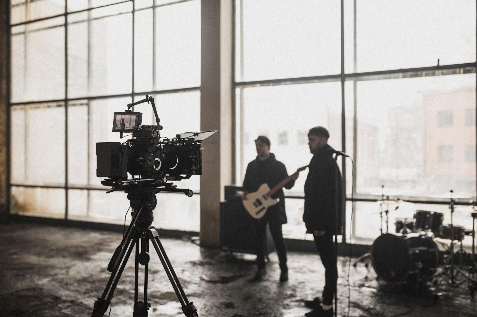 Singer and guitarist in warehouse with film camera