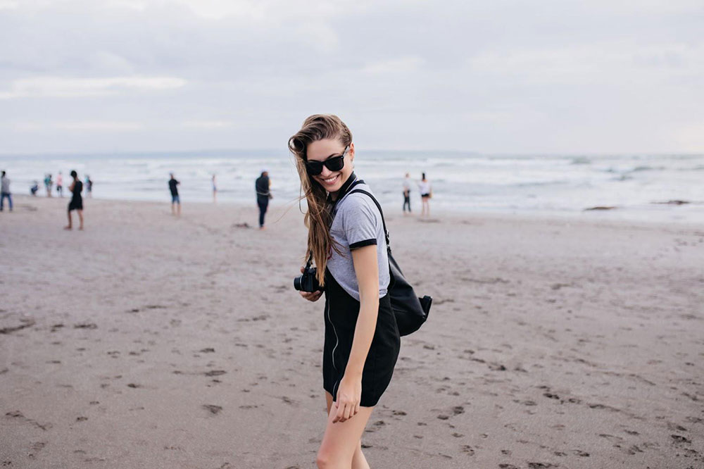 Happy young woman at beach on cloudy day