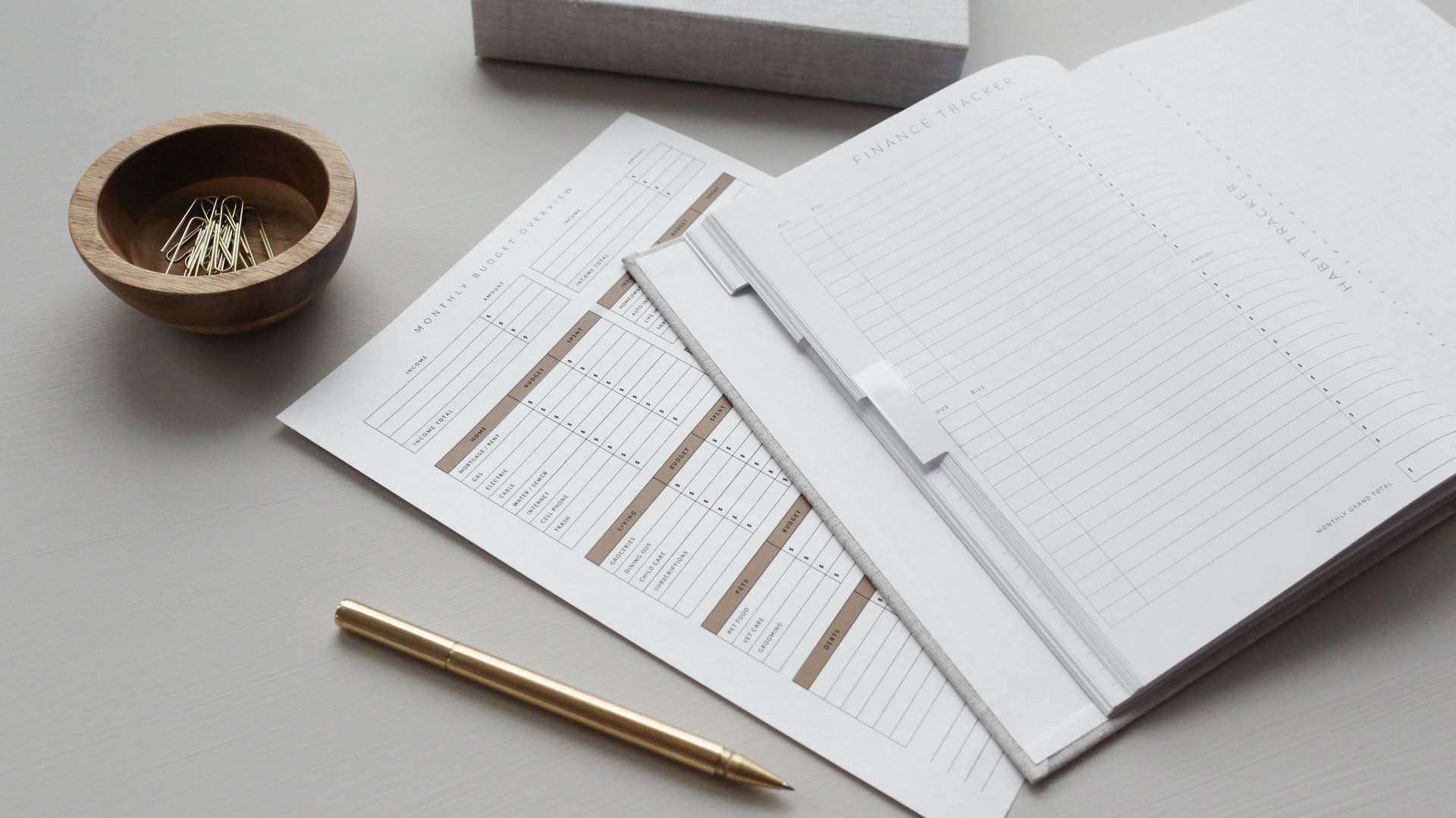 budgeting documents on table with pen and paperclips